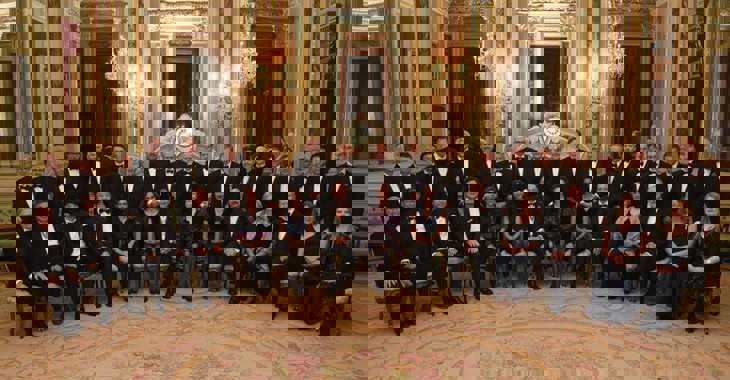 Formal group shot of 33 people, in black tie, facing camera in two rows